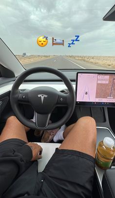 a person sitting in the driver's seat of a car with their feet on the steering wheel