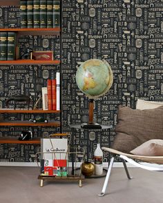 a chair and bookshelf in front of a wall with a globe on it