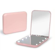 a pink laptop computer sitting on top of a white table next to a mirror and mouse pad