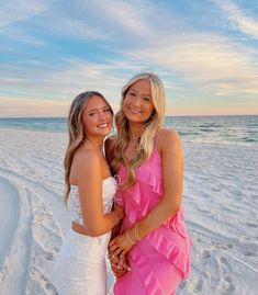 two beautiful young women standing next to each other on a beach