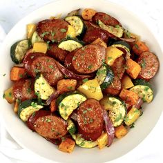 a white bowl filled with sausage and veggies