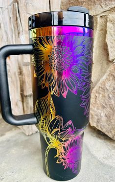 a colorful coffee cup sitting on top of a stone floor next to a rock wall