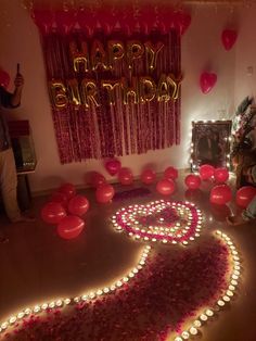 a birthday party with candles and balloons in the shape of a heart on the floor