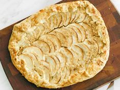 a wooden cutting board topped with an apple pie