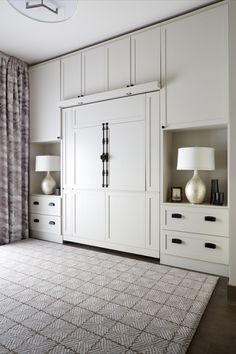 a room with white cabinets and lamps on the wall next to a large carpeted rug