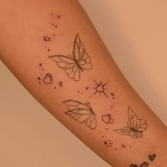 a woman's arm with tattoos on it and two butterflies flying in the sky