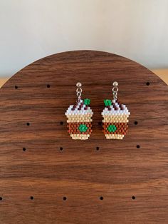 a pair of earrings made out of legos sitting on top of a wooden table