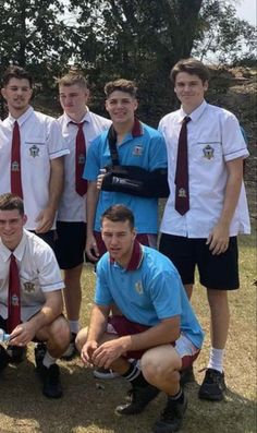 a group of young men standing next to each other on top of a grass covered field