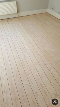 an empty room with hard wood flooring and white radiator in the corner