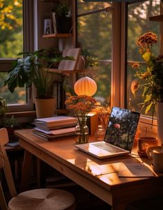 an open laptop computer sitting on top of a wooden desk next to a plant filled window