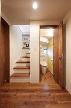 an open door leading to a bathroom with wooden floors and white walls, along with stairs