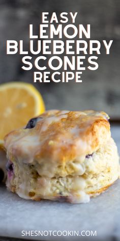 An image of a Lemon Blueberry Scone, drizzled with a light glaze resting on a grey marble board. A sliced lemon sits in the background as garnish. The purpose of this image is to show the completed recipe. Oreo Scones Recipe, Blueberry Scone Recipes, Scones Made With Buttermilk, Blueberry Tea Biscuits, Blueberry Scones With Buttermilk, What To Bake With Buttermilk, Awrey Bakery Recipes, Lemon Brunch Recipes, Buttermilk Blueberry Scones