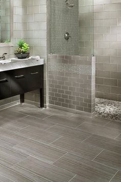 a bathroom with a sink, mirror and shower in it's center area that has grey tile on the floor