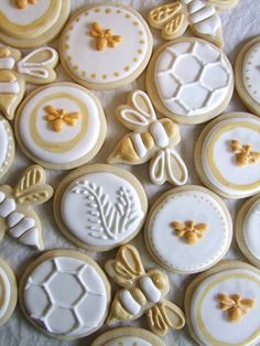 many decorated cookies on a table with white and gold decorations in the middle, including bees