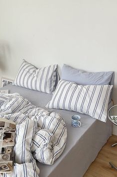 an unmade bed with blue and white striped pillows