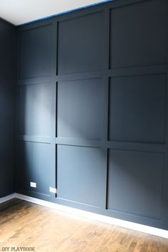 an empty room with dark blue walls and wood flooring, painted in the same color