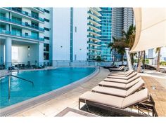 an outdoor swimming pool with lounge chairs next to it