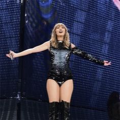 the singer is performing on stage with her legs spread out and hands outstretched in front of her