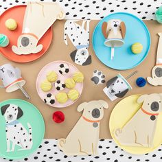 paper plates with dogs on them are arranged on a tablecloth covered surface, along with cupcakes and other decorative items