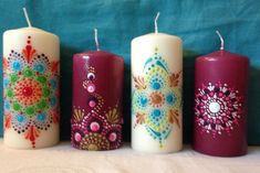 three candles with different designs on them are lined up against a blue background, one is white and the other is red