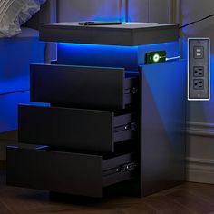 an electronic device is sitting on top of some drawers in front of a blue light