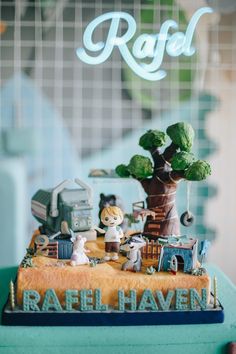 a close up of a cake on a table with trees and animals in the background