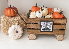 pumpkins and gourds are sitting in a wooden crate on the shelf next to hay bales