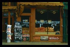 a store front with oranges on display in the window and other signs behind it