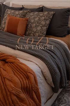 a bed with orange and grey blankets on top of it