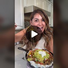 a woman making a funny face while holding a skillet filled with food