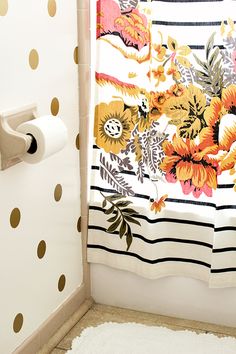 a shower curtain in a bathroom with polka dots on the wall and sunflowers