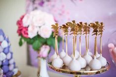 there are many small white balls on a gold platter and some pink flowers in the background