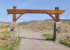 a wooden sign that is on the side of a road in front of some hills