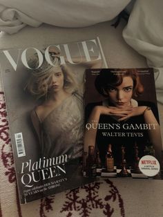 two magazines sitting on top of a bed next to each other