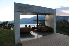 an outdoor chapel overlooking the water and mountains is shown in this image, with benches at the end of the aisle