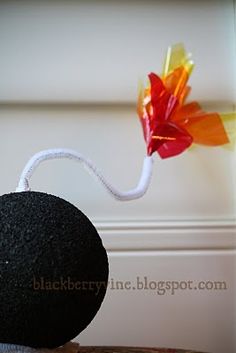 a black ball with a flower on it sitting on top of a wooden table next to a wall