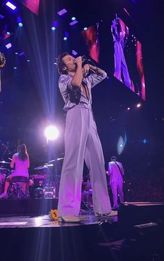 a man standing on top of a stage with his hands in the air while holding a microphone