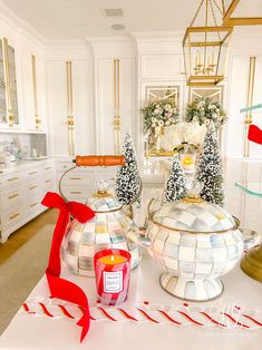 two tea kettles sitting on top of a table with red ribbon around them and christmas decorations in the background