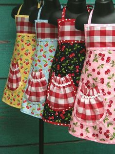 four aprons are lined up on a rack