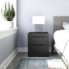 a bed room with a neatly made bed and a night stand next to a window