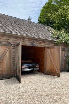 an old car is parked in the open garage door that has been opened to let people inside