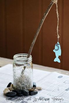 a glass jar filled with sand next to a tree branch and some sea shells on top of a table