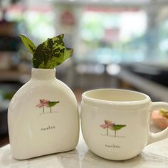 two cups with leaves on them sitting on a table