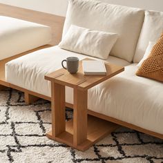 a coffee cup on a table next to a white couch with pillows and a pillow