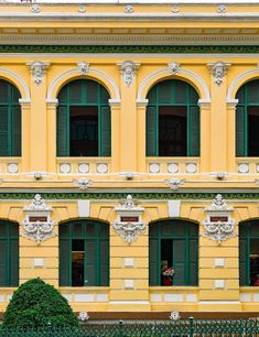 an old yellow building with green shutters and windows