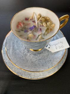 a tea cup filled with flowers sitting on top of a saucer next to a price tag