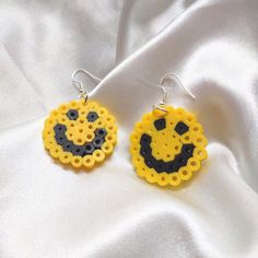 the earrings are made out of plastic beads and have smiley faces on them, sitting on a white fabric