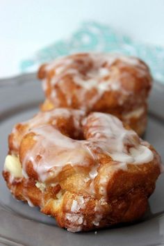 two glazed donuts sitting on top of a gray plate