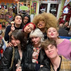 a group of young people posing for a photo in front of a store filled with candy