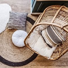 an overhead view of a wicker basket with pillows and rugs on the floor